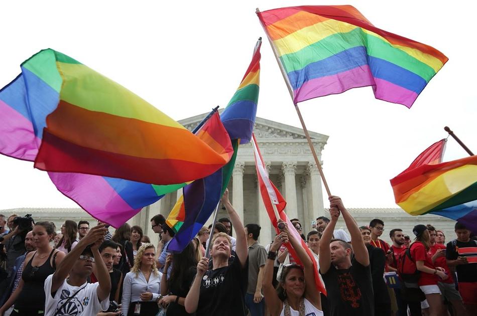 people waving Pride rainbow flags in front of the U.S. Supreme Court